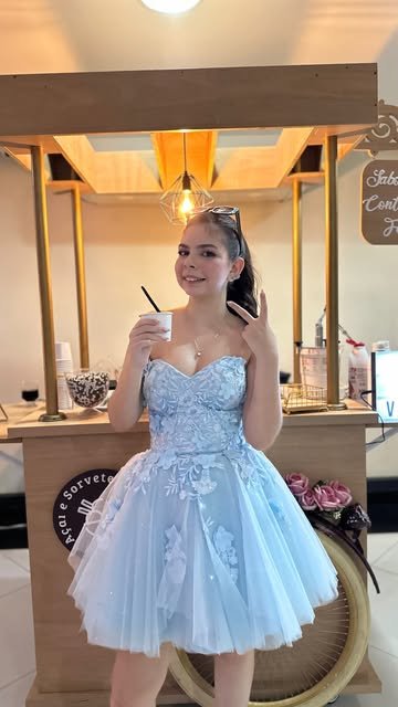 Debutante de vestido azul ao lado do carrinho de açaí
